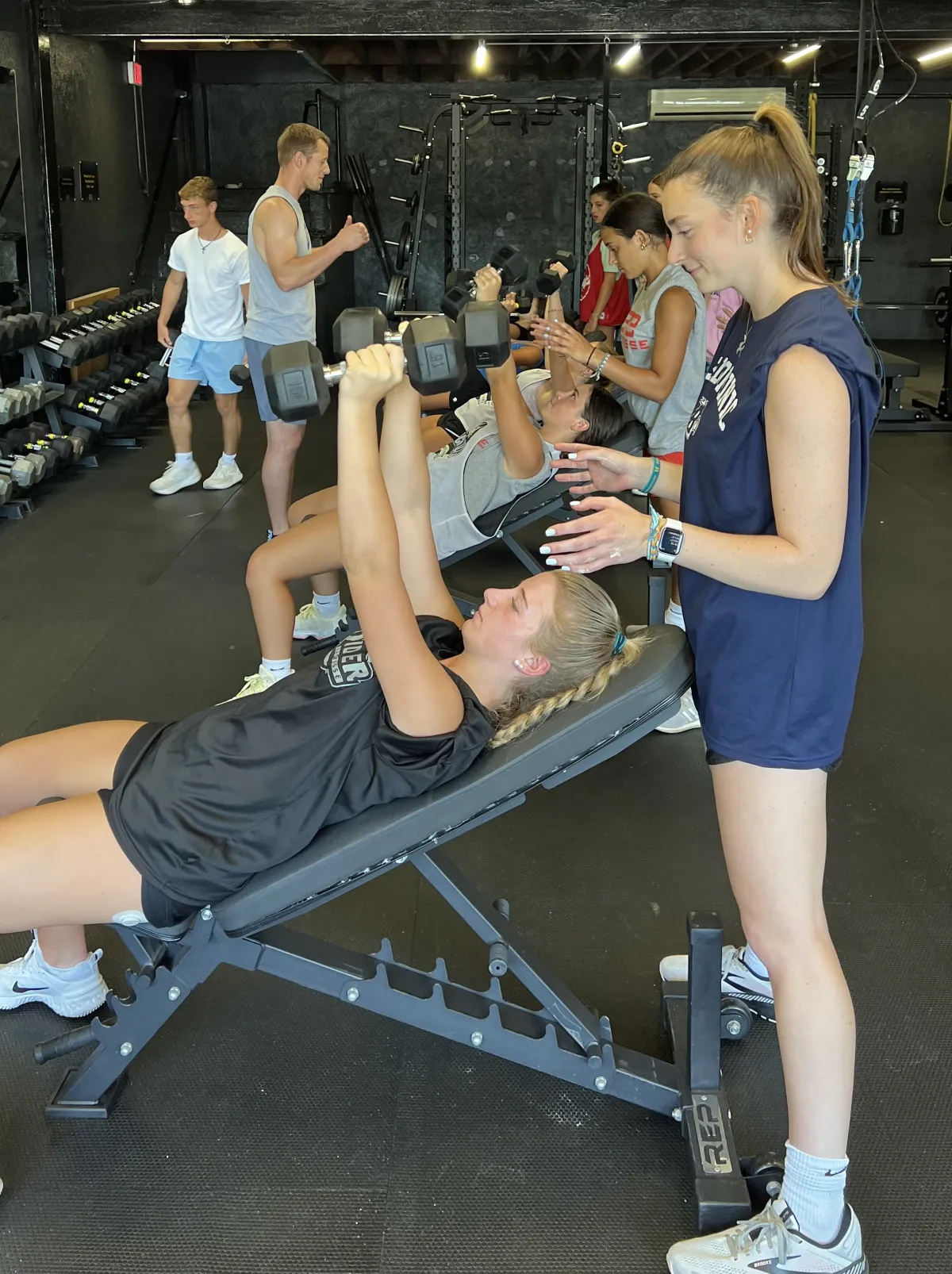 LI Thunder Softball athlete pressing dumbbells with a teammate spotting